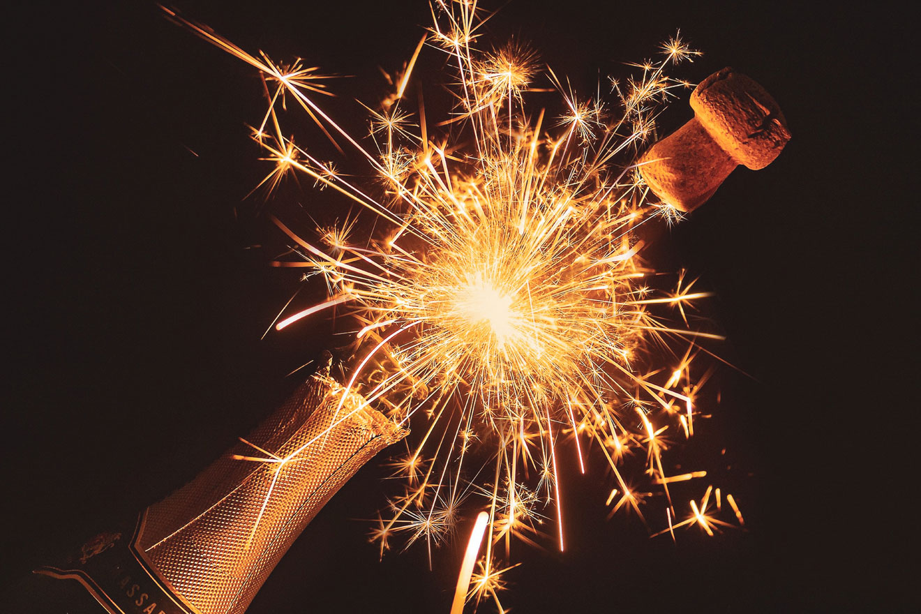 a photo showing a popping champagne bottle and sparkling fireworks