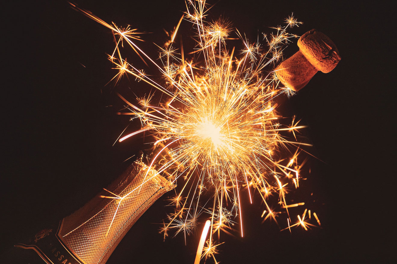a photo showing a champagne bottle popping and sparkling fireworks
