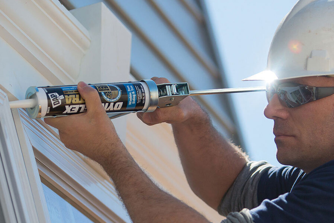 a photo of a worker using a DAP sealant product on an exterior window