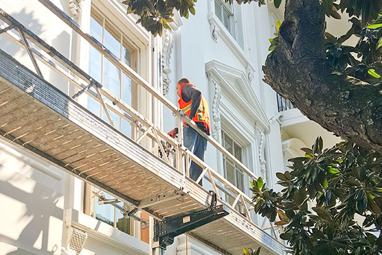 a photo of a worker on a ReechCraft lift alongside the exterior of a building
