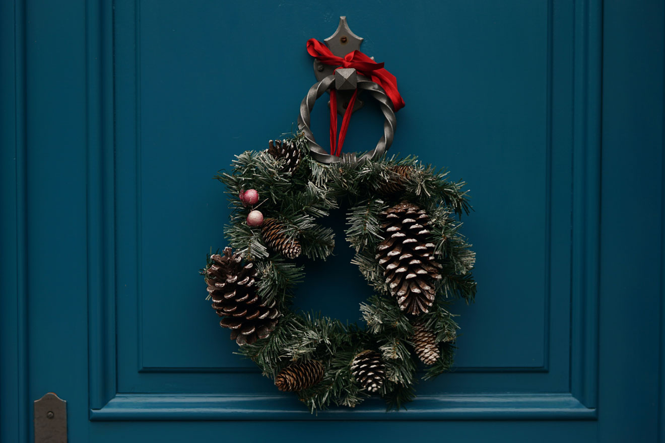 a photo showing a Christmas wreath hanging on a blue door